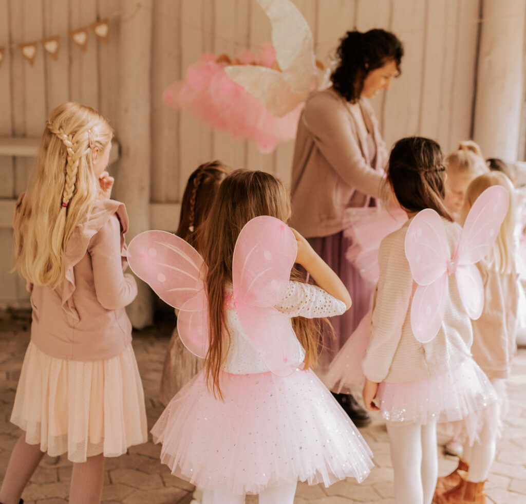 Mädchen legen für den Feengeburtstag rosafarbene Feenflügel an.